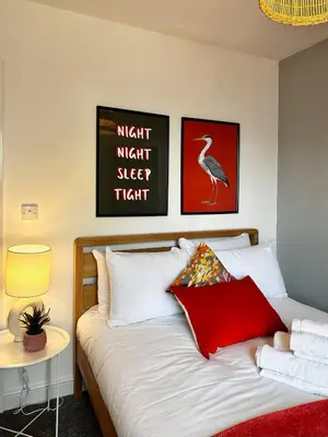 a bedroom with a bed with red and white pillows at Ideal Wigan Base - 1BR for Cosy Stays in Wigan