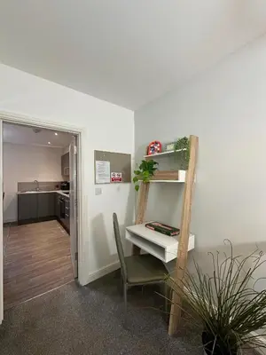 a room with a desk and a chair and a kitchen at Ideal Wigan Base - 1BR for Cosy Stays in Wigan
