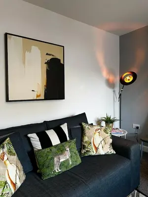 a living room with a blue couch with pillows at Ideal Wigan Base - 1BR for Cosy Stays in Wigan