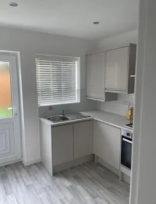 a kitchen with white cabinets and a sink and a window at blackburn home in Blackburn