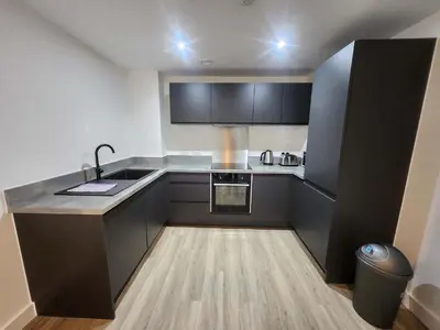 a small kitchen with black cabinets and a sink at Modern & Bright 2 Bedroom Apartment in Liverpool in Liverpool