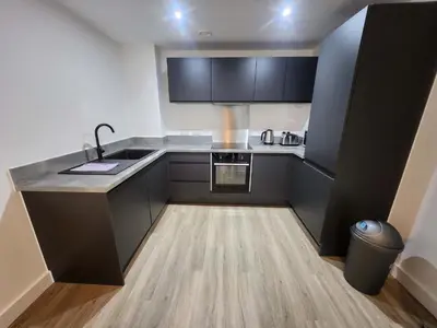 a small kitchen with black cabinets and a sink at Modern & Bright 2 Bedroom Apartment in Liverpool in Liverpool