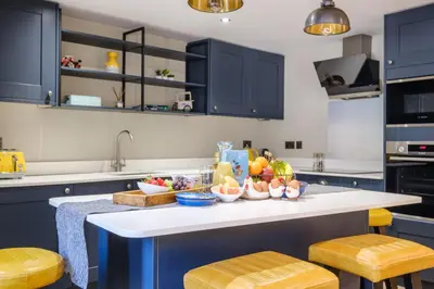 a kitchen with blue cabinets and a counter with bowls of fruit at Ivy Cottage in Silverdale