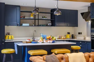 a kitchen with blue cabinets and a table with fruits on it at Ivy Cottage in Silverdale