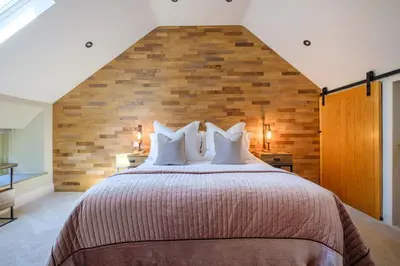 a bedroom with a large bed with a brick wall at Ivy Cottage in Silverdale