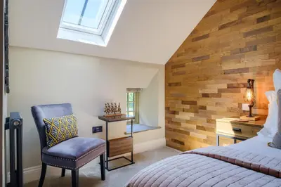 a bedroom with a bed and a chair and a window at Ivy Cottage in Silverdale