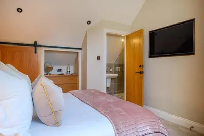 a bedroom with a bed with a television on the wall at Ivy Cottage in Silverdale