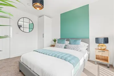 a white bedroom with a large bed with blue accents at The Vintara Suite - Central - 2Bed - Cozy Stay in Liverpool