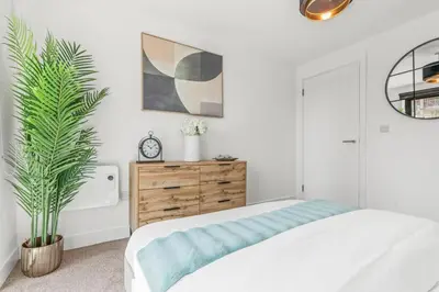 a white bedroom with a bed and a plant at The Vintara Suite - Central - 2Bed - Cozy Stay in Liverpool