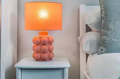 an orange lamp sitting on a table next to a bed at GuestReady - Stylish getaway in Liverpool in Liverpool