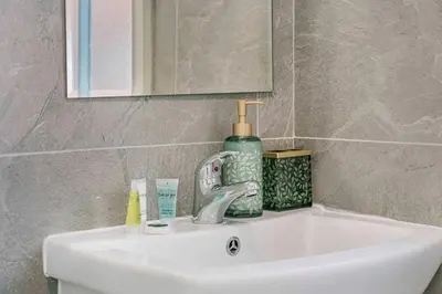 a bathroom sink with a bottle of soap and a mirror at GuestReady - Stylish getaway in Liverpool in Liverpool