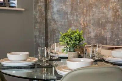 a glass table with plates and glasses on it at GuestReady - Modern stay in Liverpool city centre in Liverpool