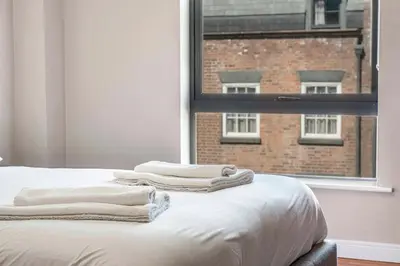 a bed with white towels on it in front of a window at GuestReady - Modern stay in Liverpool city centre in Liverpool
