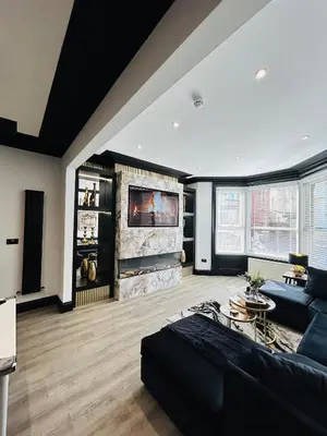 a living room with a black couch and a fireplace at New - The Fun House Blackpool - Private nightclub in Blackpool