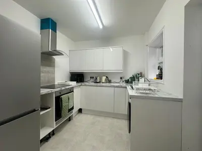 a white kitchen with white cabinets and appliances at Your Home in Southport! in Southport