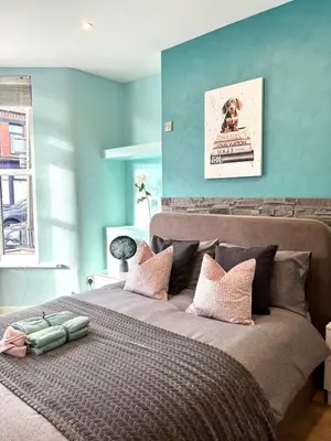 a bedroom with a large bed with blue walls at Modern Art House - serviced accomodation in Liverpool