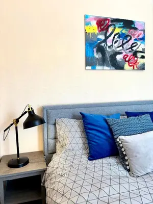 a bed with blue pillows and a table with a lamp at Modern Art House - serviced accomodation in Liverpool