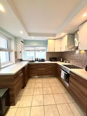 a large kitchen with wooden cabinets and a large window at Modern Art House - serviced accomodation in Liverpool
