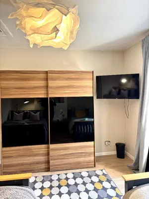 a bedroom with a bed and a large wooden cabinet at Modern Art House - serviced accomodation in Liverpool