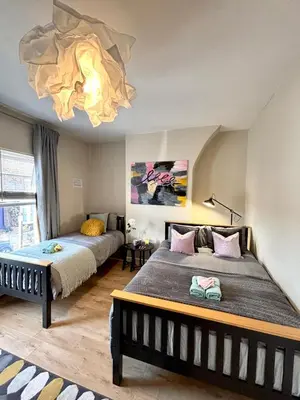 a bedroom with two beds and a chandelier at Modern Art House - serviced accomodation in Liverpool