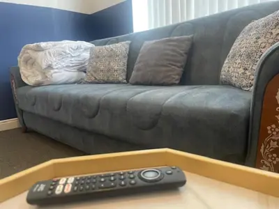 a couch with a remote control on a table at Bond Street Apartment Near the Promenade with Two Bathrooms and Workspace in Blackpool