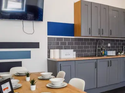 a kitchen with a wooden table with white chairs at Bond Street Apartment Near the Promenade with Two Bathrooms and Workspace in Blackpool