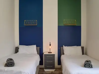 two beds in a room with blue and green walls at Bond Street Apartment Near the Promenade with Two Bathrooms and Workspace in Blackpool