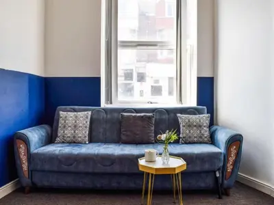a blue couch in a room with a window at Bond Street Apartment Near the Promenade with Two Bathrooms and Workspace in Blackpool
