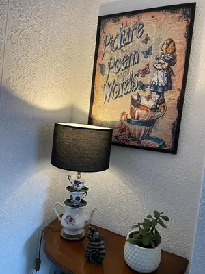 a table with a lamp and a picture of a person wonders at Alices House in Fleetwood