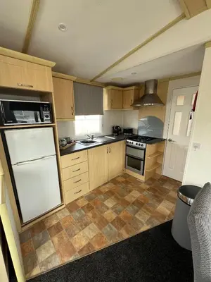 a kitchen with wooden cabinets and a white refrigerator at Seaside Getaway - Lytham Road in Warton