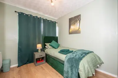 a bedroom with a bed with a green blanket and a table at Swindon Home in Liverpool
