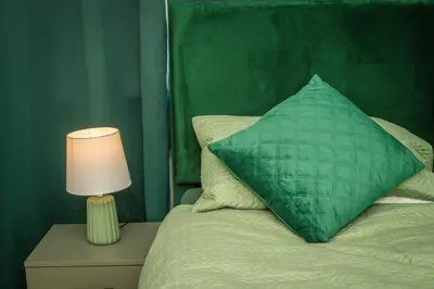 a green pillow sitting on a bed next to a lamp at Swindon Home in Liverpool