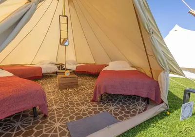 a tent with two beds and a ladder in it at Nine Yards Bell Tents - Lytham in Lytham St Annes