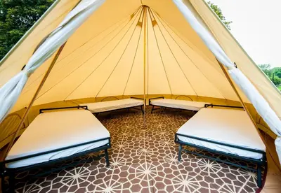two beds in a tent with a tiled floor at Nine Yards Bell Tents - Lytham in Lytham St Annes