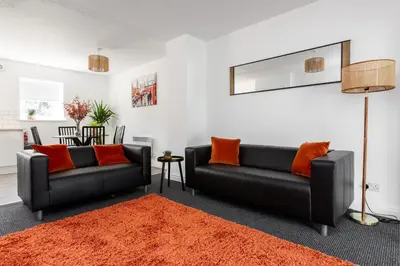 a living room with two black couches and an orange rug at Waterfront 2 Bed Apartment - Free Parking & Wi-Fi in Preston