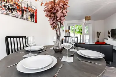 a table with plates and glasses and a vase with flowers at Waterfront 2 Bed Apartment - Free Parking & Wi-Fi in Preston