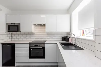 a white kitchen with a sink and a stove at Waterfront 2 Bed Apartment - Free Parking & Wi-Fi in Preston