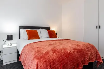 a bedroom with a large bed with orange pillows at Waterfront 2 Bed Apartment - Free Parking & Wi-Fi in Preston