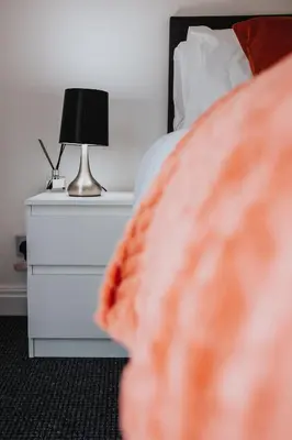 a bed with a night stand with a lamp on it at Waterfront 2 Bed Apartment - Free Parking & Wi-Fi in Preston