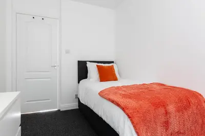 a white bedroom with a bed with an orange blanket at Waterfront 2 Bed Apartment - Free Parking & Wi-Fi in Preston