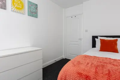 a white bedroom with a bed and a dresser at Waterfront 2 Bed Apartment - Free Parking & Wi-Fi in Preston