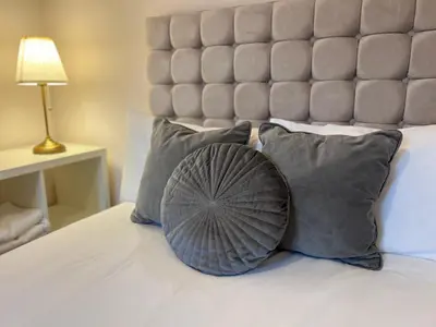 a bed with gray pillows and a large headboard at Liverpool Rose House Stylish 3 Bed Near Anfield and Goodison Park in Liverpool