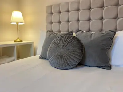 a bed with gray pillows and a large headboard at Liverpool Rose House Stylish 3 Bed Near Anfield and Goodison Park in Liverpool