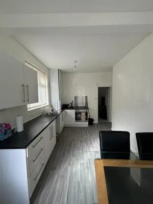 a large kitchen with white cabinets and a wooden floor at Affordable room near Anfield stadium - 5 minute walk in Liverpool