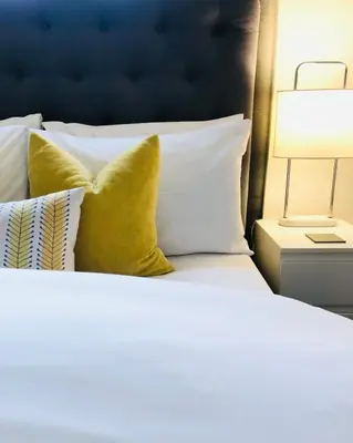a white bed with yellow pillows and a lamp at Chadberry House Hotel in Blackpool