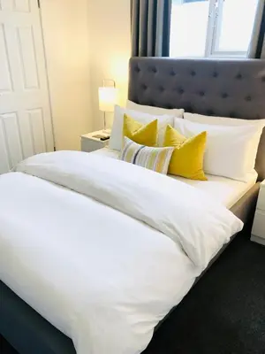 a large white bed with yellow pillows on it at Chadberry House Hotel in Blackpool