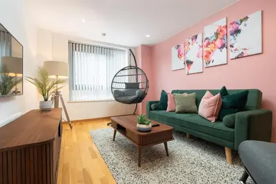 a living room with a green couch and pink walls at Central Town Retreat Modern 2BR2BA Apartment Sleeps 7 in Liverpool