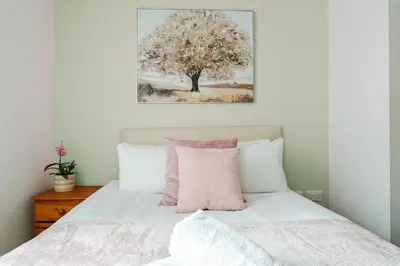 a bedroom with a bed with a tree painting on the wall at Central Town Retreat Modern 2BR2BA Apartment Sleeps 7 in Liverpool