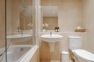 a bathroom with a sink and a tub and a toilet at Central Town Retreat Modern 2BR2BA Apartment Sleeps 7 in Liverpool