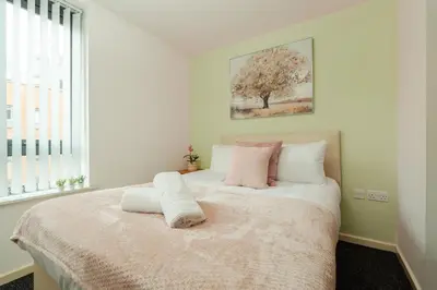 a white bedroom with a bed with pink and white pillows at Central Town Retreat Modern 2BR2BA Apartment Sleeps 7 in Liverpool